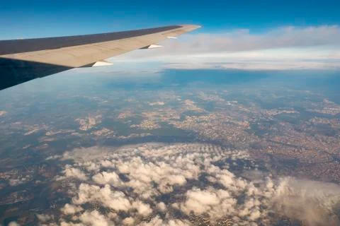 A view of land from side of plane from window. Wing of plane in porthole. Stock Photos
