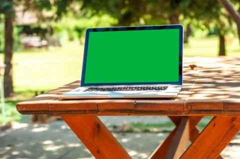 View on a laptop pc with a green screen on a table in the garden Foto stock