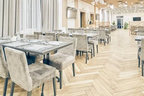 View of a large bright empty restaurant with tables, soft chairs and a wooden Stock-Fotos