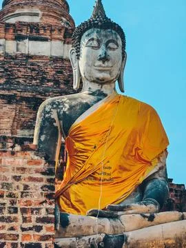 View of large Buddha statue draped in yellow robes in Ayutthaya, Thailand. Stock Photos