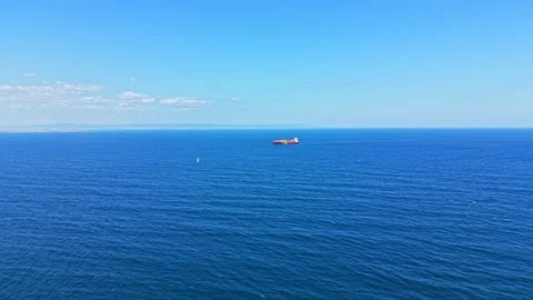 View of a large cargo ship sailing on a calm ocean under a clear blue sky from a Stock Footage 344809922