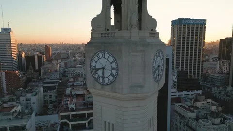 View of a large clock tower in a city at sunset with buildings around 스톡 동영상 334772667