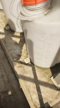 A view of a large container on a surface with shadows and pipes nearby. Stock Photos