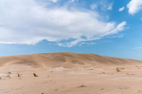 View of a large dune with the sky in the background and some clouds. Stock Photos