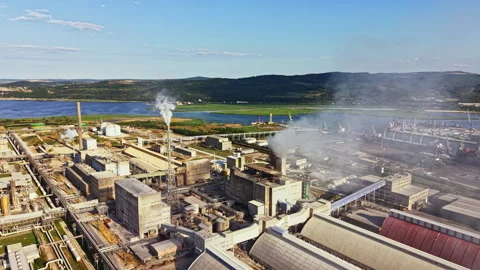 View of a large industrial complex next to a river and mountains during a clear Stock Footage 340881267