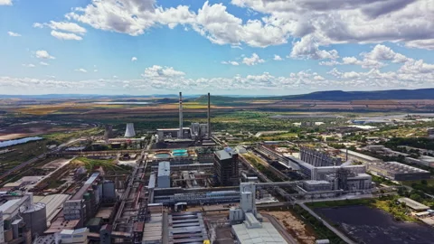 View of a large industrial complex with towers, buildings, and green fields in Stock Footage 341099238
