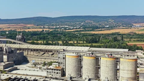 View of a large industrial facility with silos and mountains in the background Stock Footage 341097194