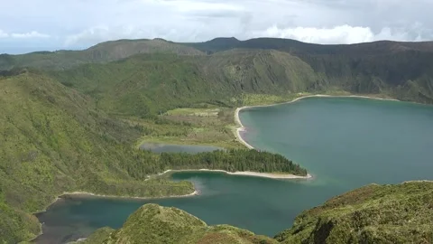 View of a large lake surrounded by green hills and trees in a natural landscape  스톡 동영상 345870535