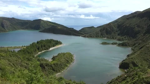 View of a large lake surrounded by green hills and trees in a natural landscape  스톡 동영상 345870536