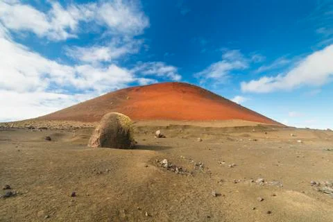 View of a large lava bomb in front of the Caldera Colorada in Lanzarote, Spai Stock Photos