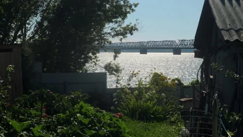 View of large river with bridge over it through old wooden house with garden Stock Footage 140671018