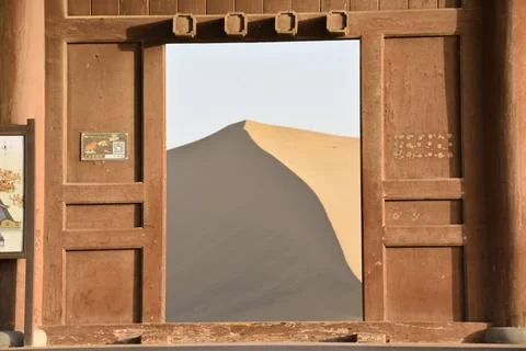 View of a large sand dune through a door in the desert at Dunhuang in China 스톡 사진