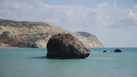 View of a large sea stack surrounded by calm water with coastal cliffs in the Stock Footage 331701796