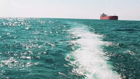 View of a large tanker ship from the wake of a fast moving motorboat Stock Footage 312039623