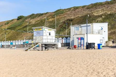 A view of a lifeguard tower on a sandy beach with beach huts Stock Photos