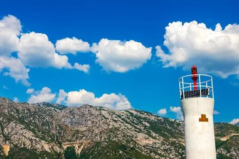 View of the lighthouse, in the background mountains, sky, snow-white clouds Stock Photos