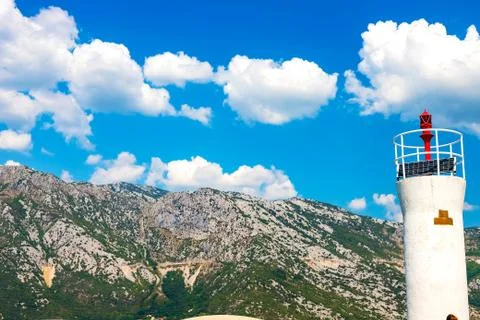 View of the lighthouse, in the background mountains, sky, snow-white clouds Stock Photos