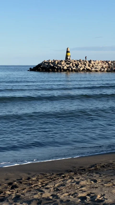 View of lighthouse from beach in Benalmadena, Malaga, Spain. Vertical video Stock Footage 240921309