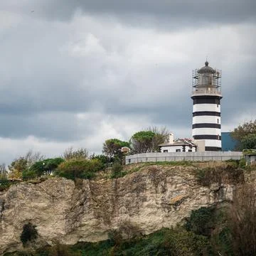 View of lighthouse at seashore against cloudy sky. Beautiful Lighthouse On Th Stock Photos