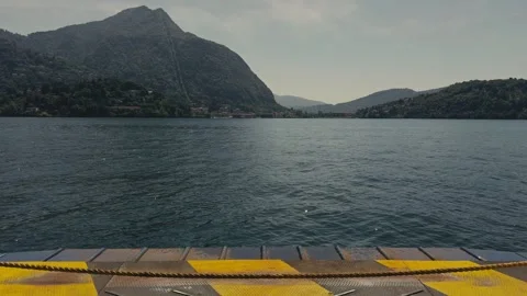 View from Loading Ramp of a Moving Ferry Across Calm Lake with Alpine Mountains Stock Footage 340901123