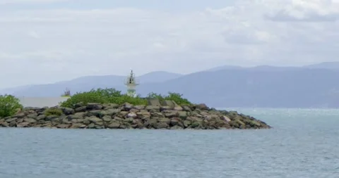 A view of a lone lighthouse in the middle of the sea with a distant shoreline Stock Footage 296585856