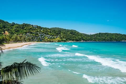 View on long large waves in the turquoise lagoon surrounded green hills. Summ Stock Photos