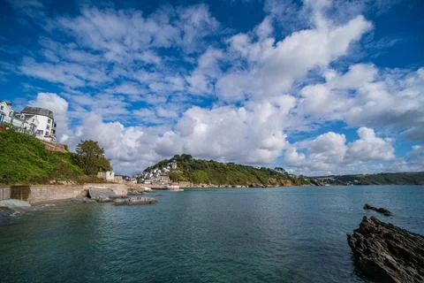 View of Looe coastline with Banjo Pier and houses on hill under blue sky 스톡 사진