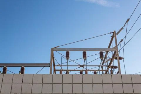 View looking up at a block wall and electrical power substation against blue Foto stock
