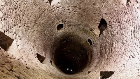 View looking down into an ancient Roman stone well inside underground catacombs Stock Footage 325741748
