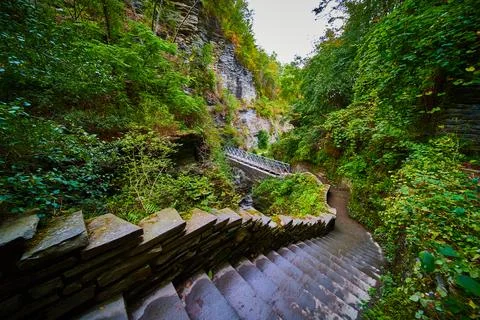View looking down stone step trail in woods leading to bridge in New York Stock-Fotos