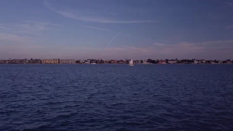 View looking east of sea wall east of Pass A Grille Way towards a white sailboat Stock Footage 262371209