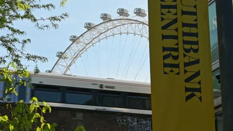 A view looking up at a railway bridge as a train passes with the London Eye i Stock Footage 159235880