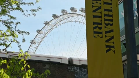 A view looking up at a railway bridge as a train passes with the London Eye i Stock Footage 168457664