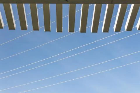View looking up through the edge of a pergola at blue sky with power lines Stock Photos