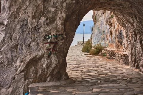 View looking through a rock tunnel on the Arvanitia coastal path toward a str Stock Photos