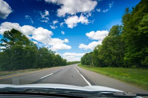 View of main road seen through car windscreen with white clouds in sky. Stock Photos