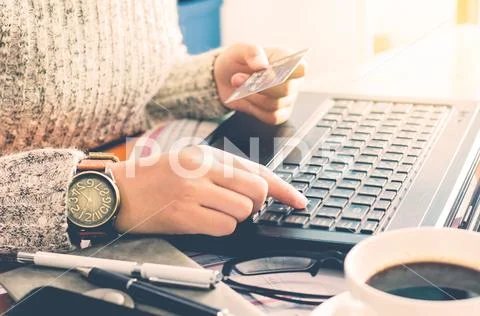 View of male hands holding credit card numbers typed on the computer keyboard wh Stock Photos