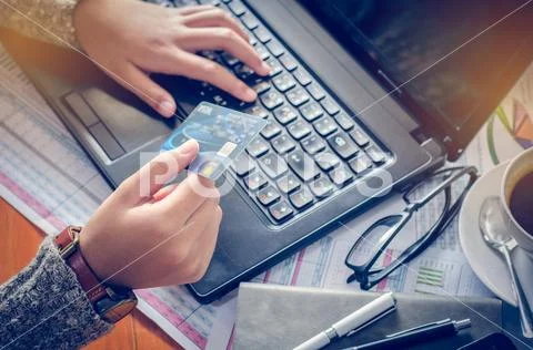 View of male hands holding credit card numbers typed on the computer keyboard wh Stock Photos