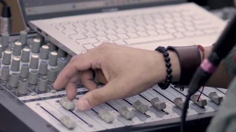 View of a man behind a laptop controlling a soundboard at an outdoor event Stock Footage 337015628