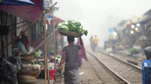 View of a man carrying cabbages on his head near tracks, Bangladesh. 動画素材 335551053