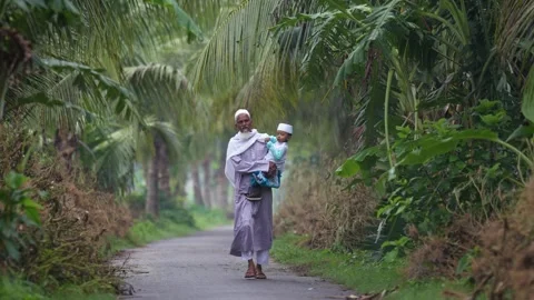 View of a man carrying a child on a path in Bogura, Bangladesh. Video stock 334991839