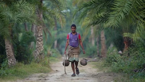 View of a man carrying clay pots on a path in Natore, Bangladesh. Видео 335652160
