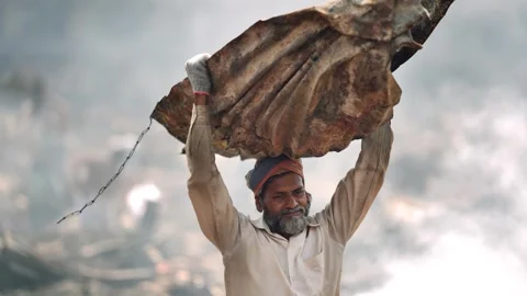 View of a man carrying heavy scrap metal on his head, Bangladesh. Stock Footage 335562777
