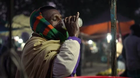 View of a man drinking from a glass at a night market, Bangladesh. Video stock 335551061