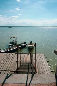View of a man by the jetty securing rope from his boat to a wooden jetty. vie Stock Photos