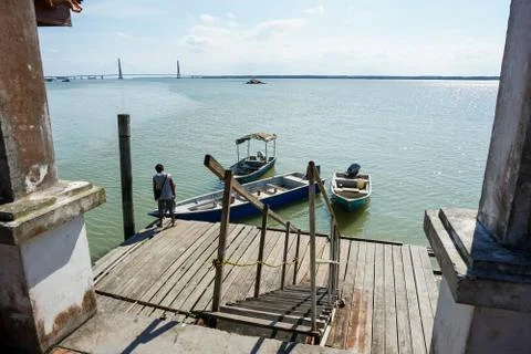 View of a man by the jetty securing rope from his boat to a wooden jetty. vie Stock Photos