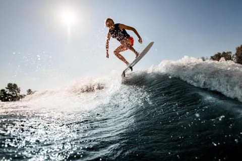View of man jumping over river wave on board against sunny blue sky. Foto stock