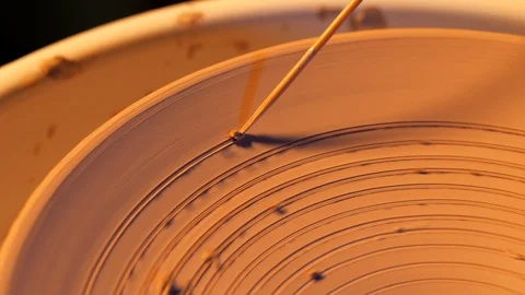 View of man making plate on pottery wheel. Potter creates a spiral pattern on it Stock Footage 97518972