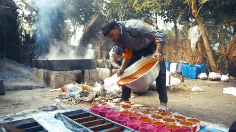 View of a man pouring liquid into molds for jaggery, Bangladesh. Video stock 335651908