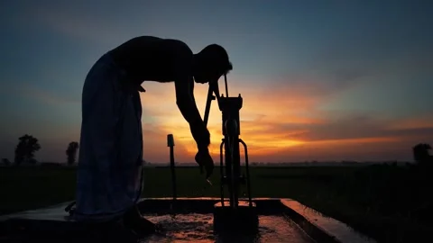 View of a man pumping water at sunset in Bogura, Bangladesh. Video stock 335553249